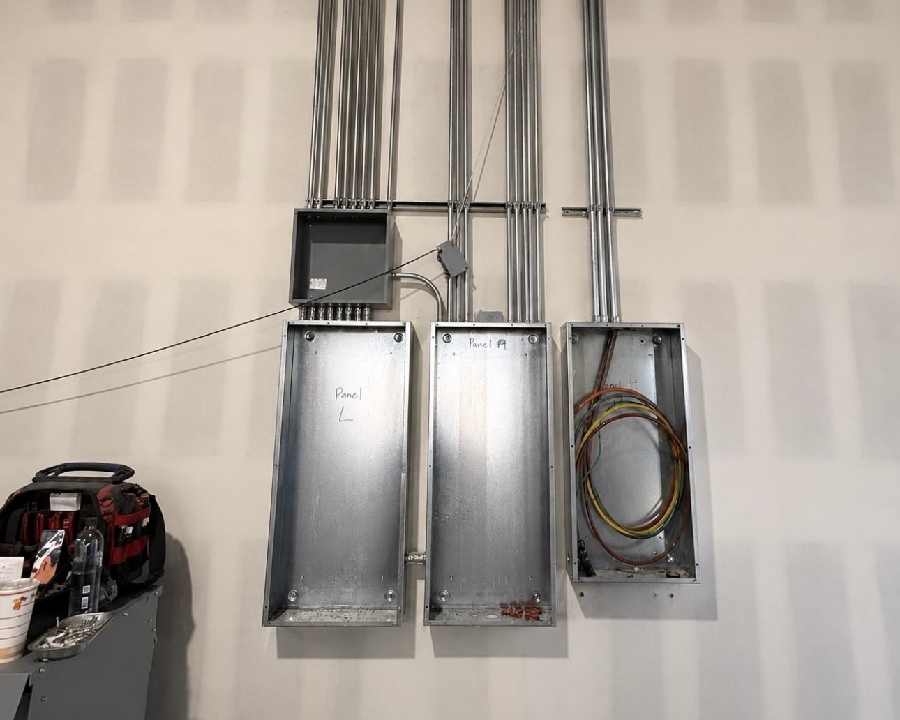 Three electrical panels and conduit rough-in on a wall